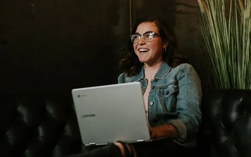 Woman with laptop smiling having a good time playing backgammon online on her computer.