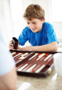 Happy little boy playing backgammon game