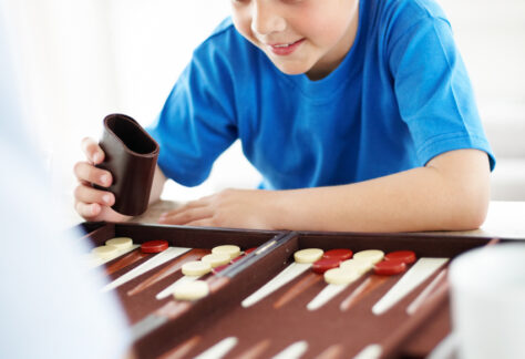Happy little boy playing backgammon game