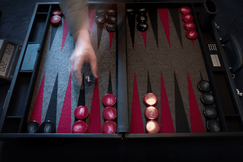 A backgammon set including a board, two sets of 15 pieces, two pairs of dice and a doubling cube.