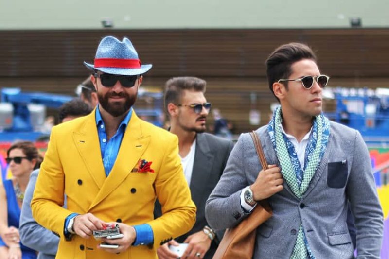 Two smartly dressed men, one dressed in colorful bold colors and the other in muted tones.