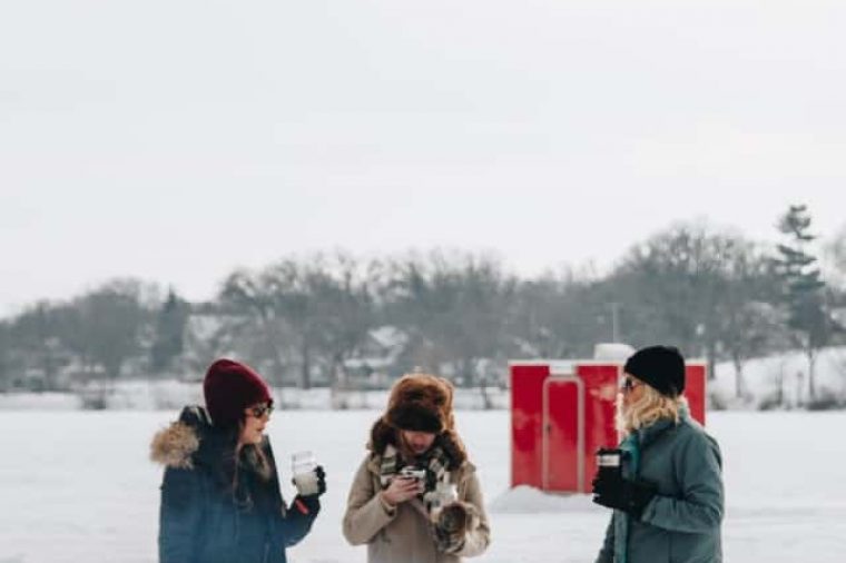 Minnesota Open: Three people standing around a fire outside in the snow